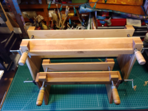 Two laying presses, which hold a book vertically with the spine up. They're wide and made of wood and have two cranks to close the jaws snugly.